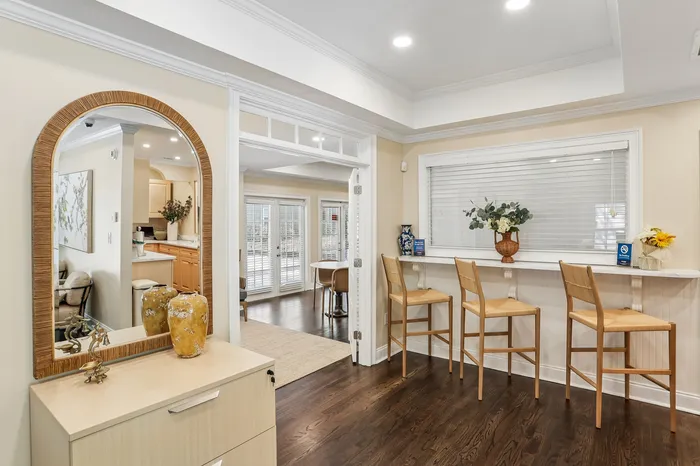 Charming apartment interior featuring a bright dining area with bar stools, elegant cabinetry, and a large mirror enhancing space and light.