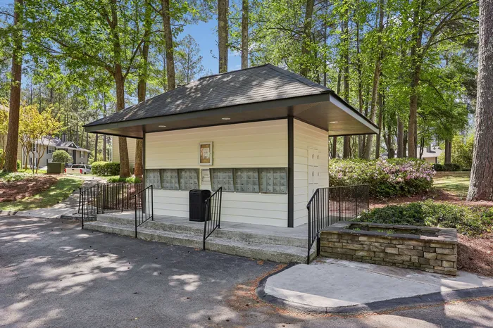 Charming community mail kiosk nestled in a serene, tree-lined setting, perfect for peaceful living.
