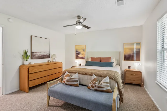 Inviting bedroom with elegant decor, featuring a cozy bed, stylish wooden dresser, and modern art pieces.