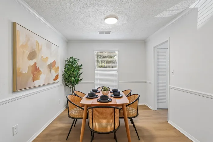 Bright and elegant dining room with a modern wooden table, stylish chairs, and vibrant abstract artwork, perfect for entertaining guests.