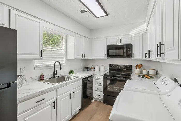 Contemporary kitchen with sleek white cabinetry, modern appliances, and elegant marble countertops.