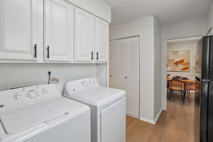 Modern laundry room with sleek appliances and ample storage, leading to a stylish dining area with contemporary artwork and elegant seating.