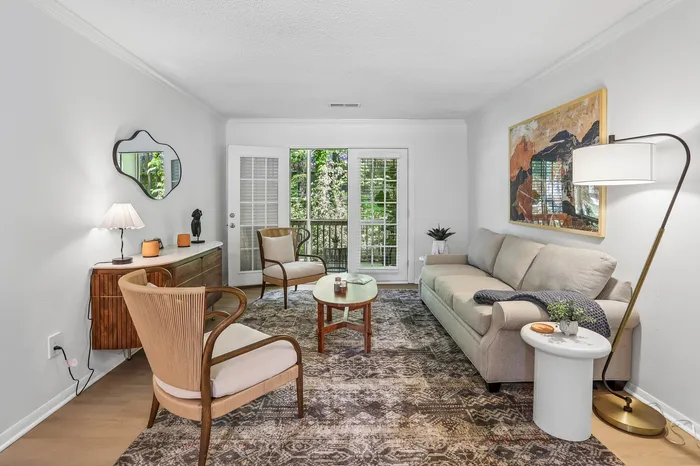 Inviting living room with elegant decor, featuring a cozy beige sofa, stylish patterned rug, and warm natural lighting from large windows.