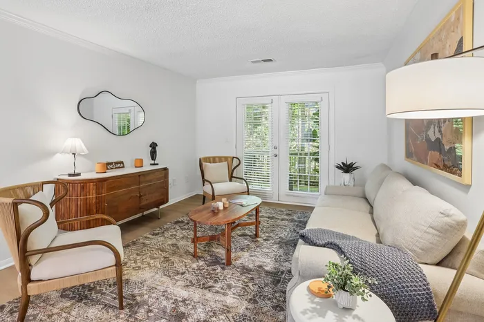 Charming living room with cozy seating, elegant wooden furniture, and natural light streaming through French doors.