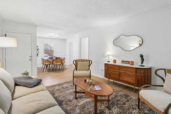 Charming living room with cozy beige sofa, elegant wooden furniture, and a tasteful dining area, exuding warmth and style.