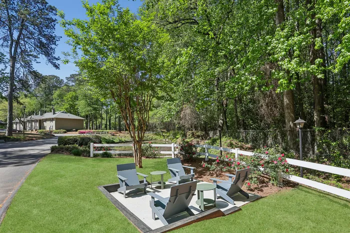 Charming outdoor seating area surrounded by lush greenery and blooming roses, perfect for relaxation and enjoying nature's tranquility.