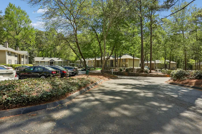 Charming apartment complex nestled in lush greenery, featuring spacious parking and serene surroundings.
