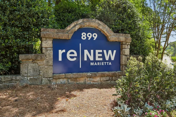 Inviting stone signage with 'reNEW Marietta' welcomes you to a vibrant community surrounded by lush greenery.