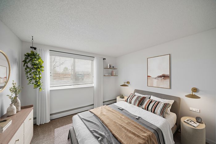 Bright and inviting bedroom featuring a cozy bed with stylish throw pillows, modern wall sconces, and lush greenery by the window, creating a serene and elegant ambiance.