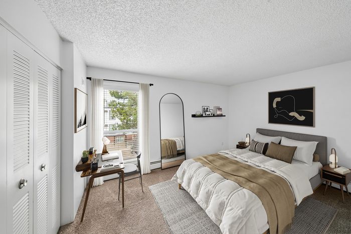 Elegant bedroom showcasing a cozy bed with stylish decor, a sleek desk by the window, and abundant natural light.
