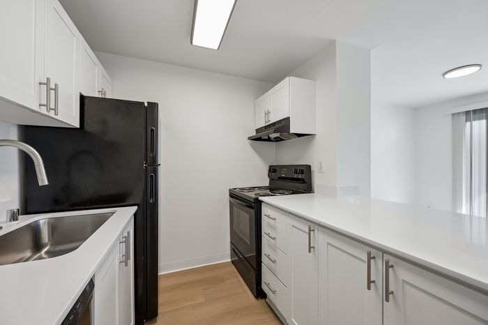 Modern kitchen with sleek black appliances, white cabinetry, and polished countertops, creating an inviting culinary space.