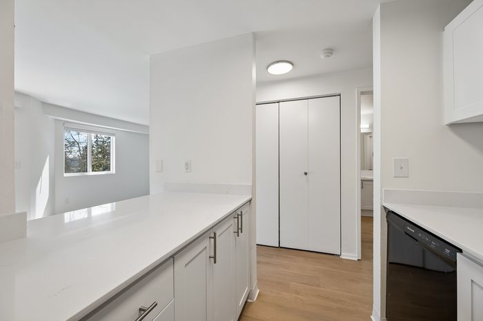 Bright modern kitchen with sleek white cabinetry, elegant countertops, and natural light streaming through large windows creating an inviting space.