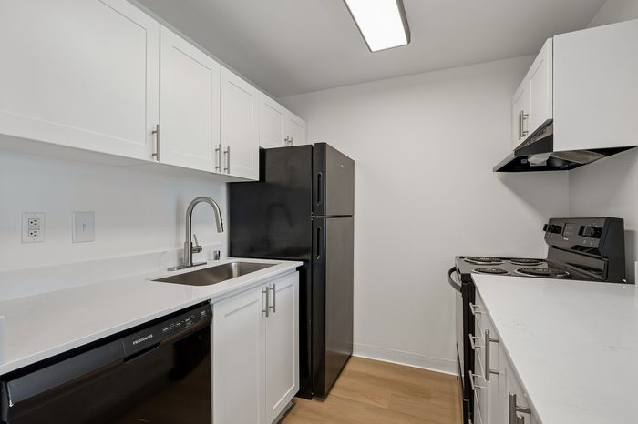 Modern kitchen with sleek black appliances, elegant white cabinetry, and polished countertops.