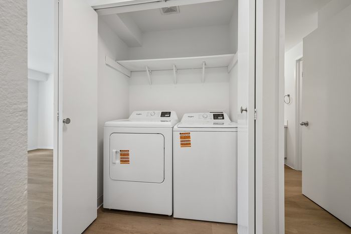 Dedicated laundry closet featuring modern washer and dryer set with ample shelving, enhancing convenience in your new home.