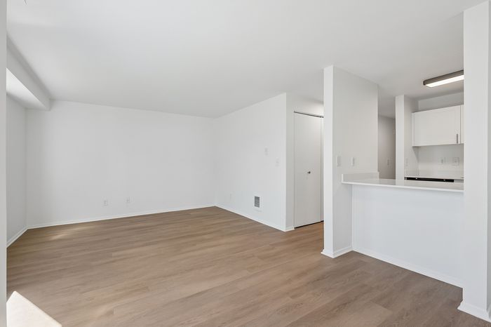 Bright and spacious open floor plan with elegant wooden flooring and sleek modern kitchen design.