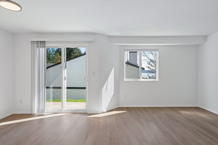 Bright and airy apartment living room with large windows, showcasing modern flooring and scenic outdoor views.
