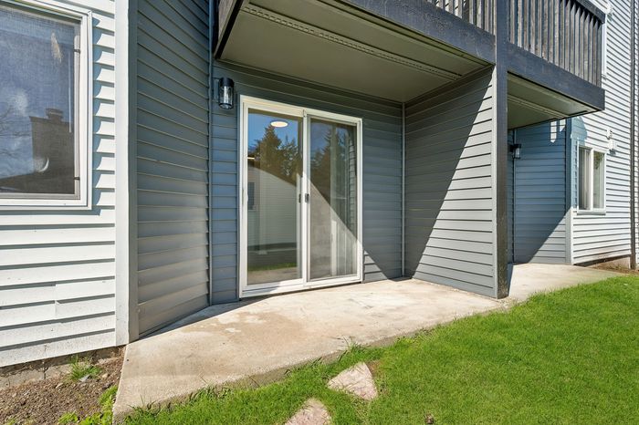 Inviting backyard with a sleek sliding glass door, modern siding, and fresh green lawn, perfect for outdoor relaxation.