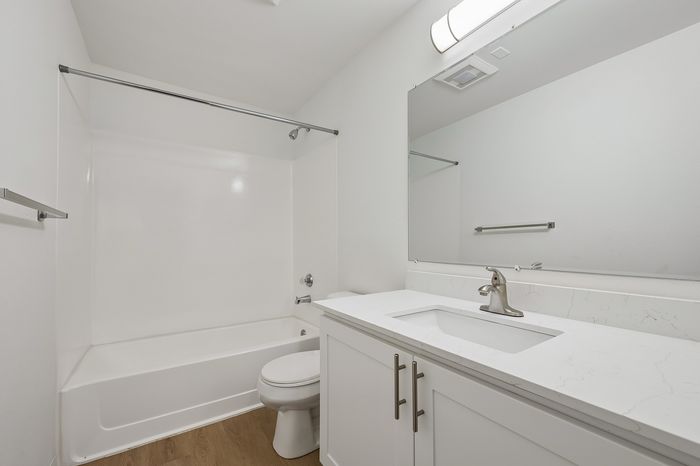 Modern bathroom with sleek white cabinets, elegant marble countertop, and a spacious bathtub.