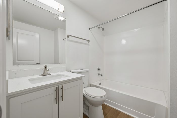 Modern, bright bathroom with sleek white cabinetry, elegant countertop, and a bathtub for relaxation.