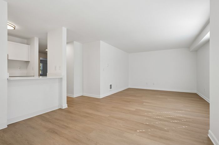 Bright, open living space with sleek hardwood floors and a modern kitchen pass-through, perfect for entertaining.