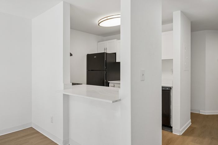 Contemporary kitchen with sleek black appliances, white cabinetry, and elegant marble countertops.