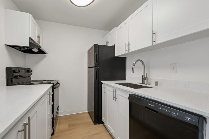 Modern kitchen with sleek black appliances, bright white cabinetry, and elegant countertops, offering a stylish and functional space.