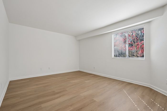 Bright and airy room with pristine hardwood flooring, large window, and scenic outdoor view showcasing vibrant red foliage.