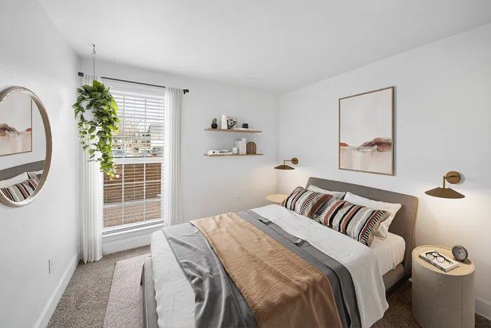 Bright and cozy bedroom with a modern aesthetic, featuring a comfortable bed, stylish wall art, floating shelves, and a large window with natural light.