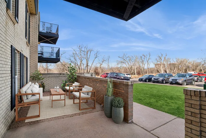 Charming outdoor patio area with elegant seating, surrounded by lush greenery, perfect for relaxation and outdoor gatherings.