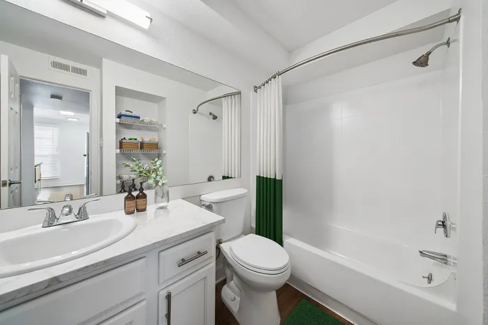 Bright and elegant bathroom featuring a modern sink vanity, stylish shelving, and a pristine bathtub with a chic shower curtain.