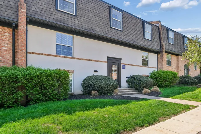 Charming townhouse exterior with lush green landscaping, modern architecture, and inviting entryway.