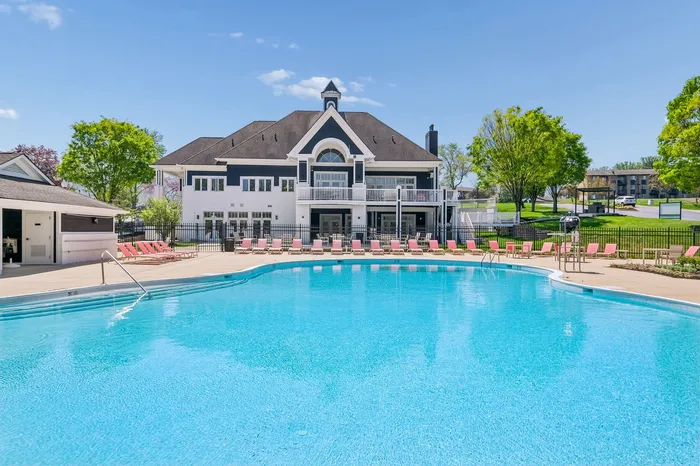 Luxurious apartment complex with a sparkling blue pool, surrounded by lush greenery and elegant architecture, perfect for relaxation and recreation.