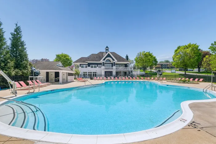 Inviting outdoor pool area with sun loungers and scenic clubhouse setting.