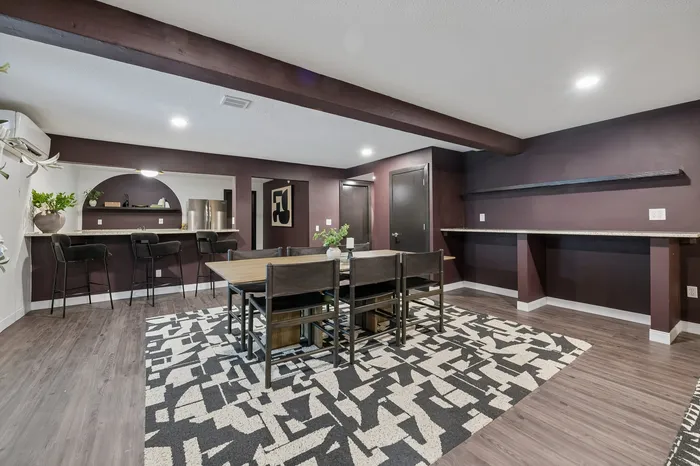 Chic dining area with modern bar stools, elegant dark walls, and stylish geometric rug for a sophisticated ambiance.