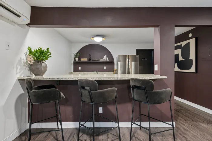 Chic kitchen space with a modern granite-topped breakfast bar, plush seating, and sophisticated wall accents.