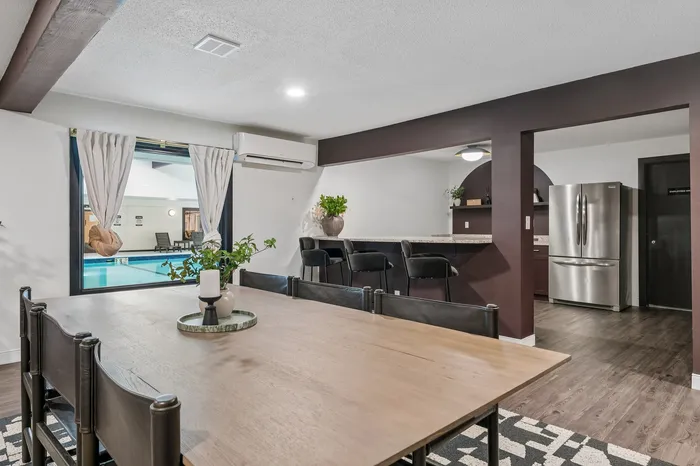 Modern open-concept dining and kitchen area with large window view of indoor pool, featuring sleek decor and stainless steel appliances.