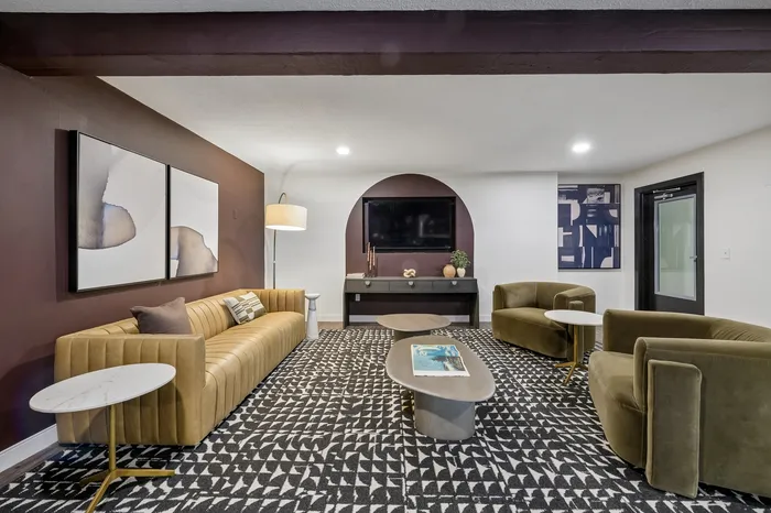 Modern living room with stylish furniture, featuring a plush mustard sofa, two olive green chairs, geometric patterned carpet, and chic wall art, creating a cozy and elegant atmosphere.