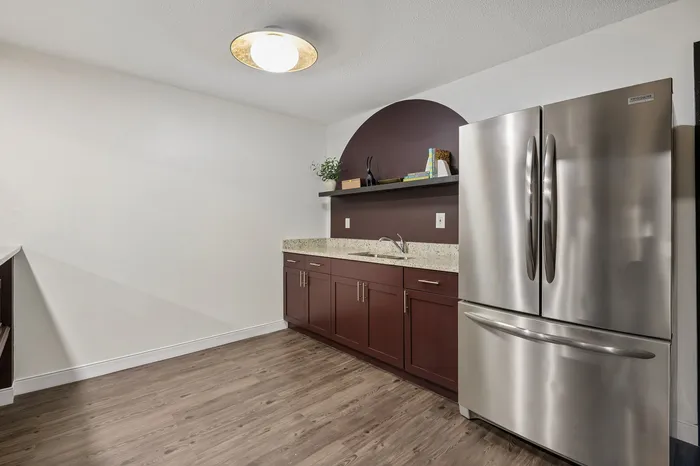 Contemporary kitchen with sleek stainless steel fridge, elegant wood cabinets, and a minimalist countertop design.