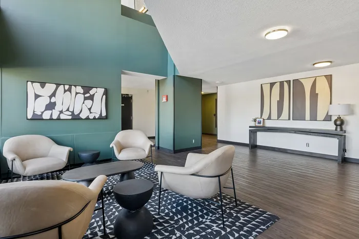 Elegant lounge area featuring modern armchairs, chic abstract artwork, and stylish decor with a calming green accent wall.