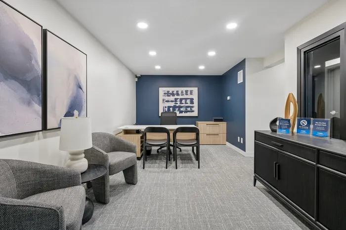 Modern office space with elegant decor, featuring minimalist furniture, stylish artwork, and ambient lighting for a professional atmosphere.