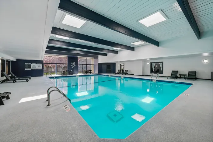 Luxurious indoor pool area with sleek modern design, skylights, and comfortable seating, offering a relaxing retreat.