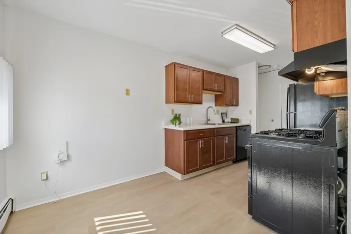 Bright, modern kitchen with sleek black appliances, elegant wood cabinetry, and light wood flooring, perfect for culinary creativity.