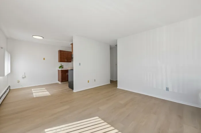 Bright and airy apartment featuring sleek hardwood floors, a cozy kitchen with wooden cabinets, and a spacious open layout.