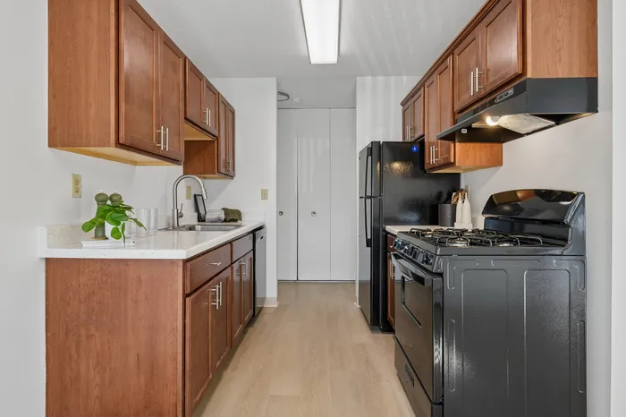 Elegant kitchen design featuring rich wooden cabinets, sleek black appliances, and a modern countertop, embodying functionality and style.
