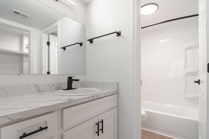 Elegant bathroom with sleek marble countertop, stylish black fixtures, and a pristine bathtub, offering a luxurious and modern design.