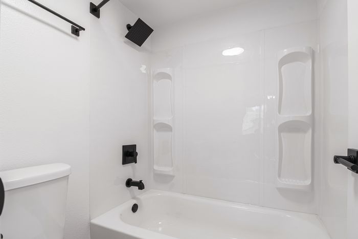 Modern bathroom featuring a sleek white bathtub and chic black fixtures, offering a stylish and tranquil retreat.
