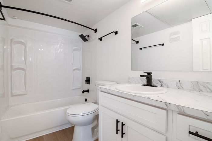 Elegant bathroom with modern fixtures, marble countertop, and a sleek bathtub with rainfall showerhead.