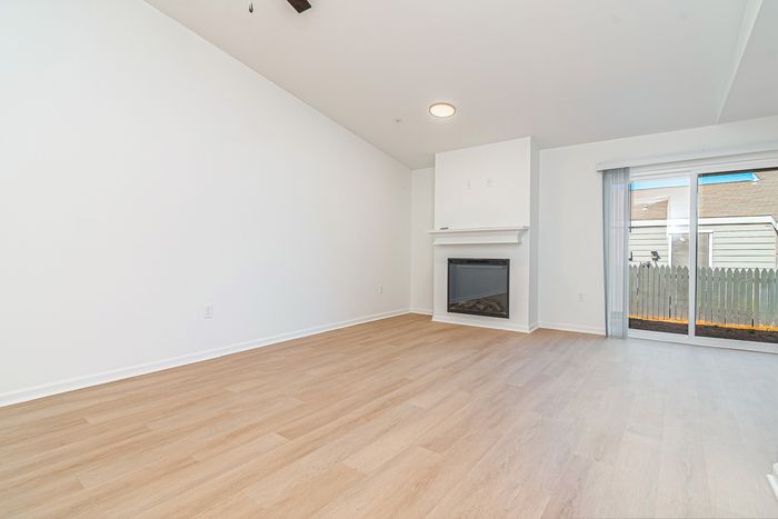 Inviting living room with modern fireplace and elegant wood flooring, featuring natural light from sliding glass doors.