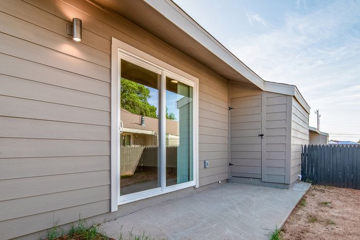 Inviting outdoor patio space with modern siding and sliding glass doors, perfect for relaxation and entertaining.