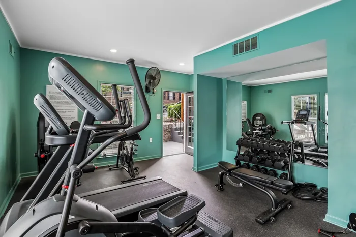 Modern apartment gym boasting state-of-the-art exercise equipment and vibrant teal walls for an energizing workout experience.